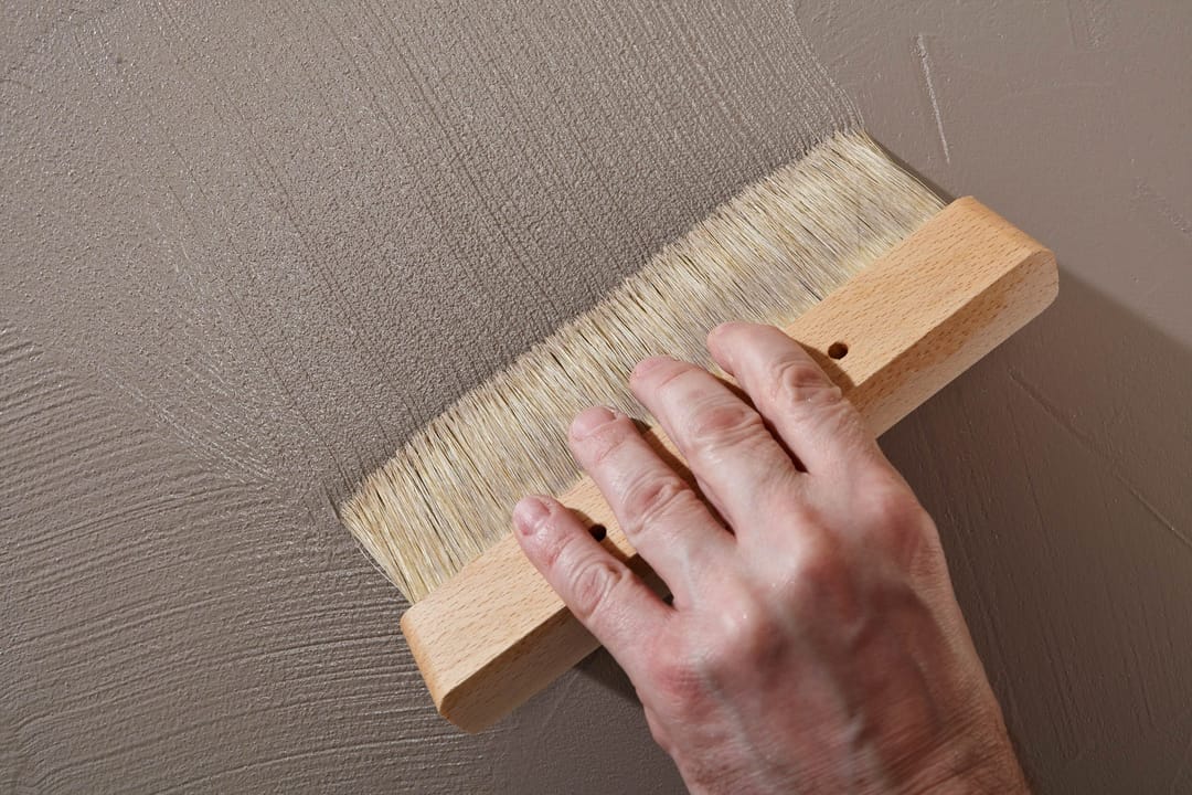 Hand streicht Wand mit Pinsel