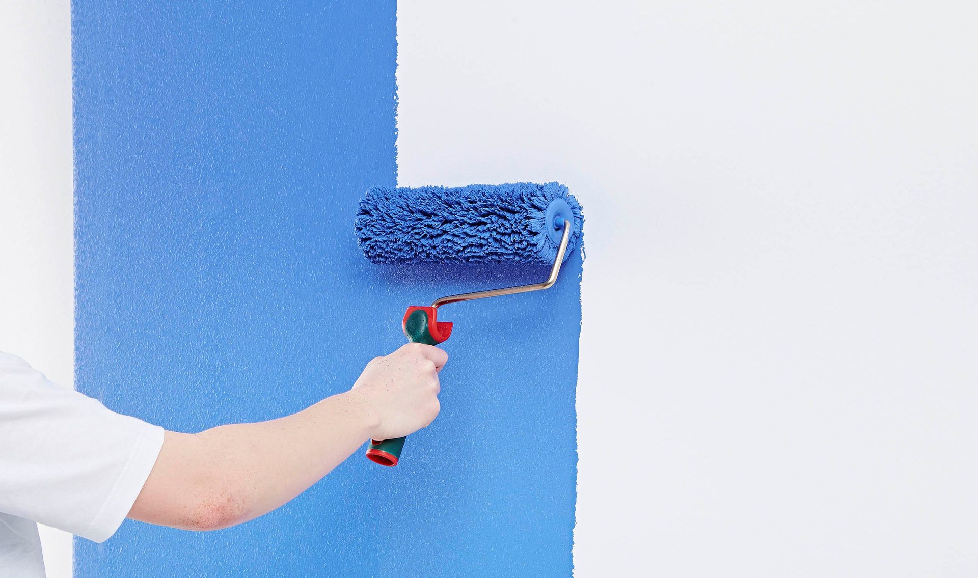 Eine Person streicht eine Wand blau.
