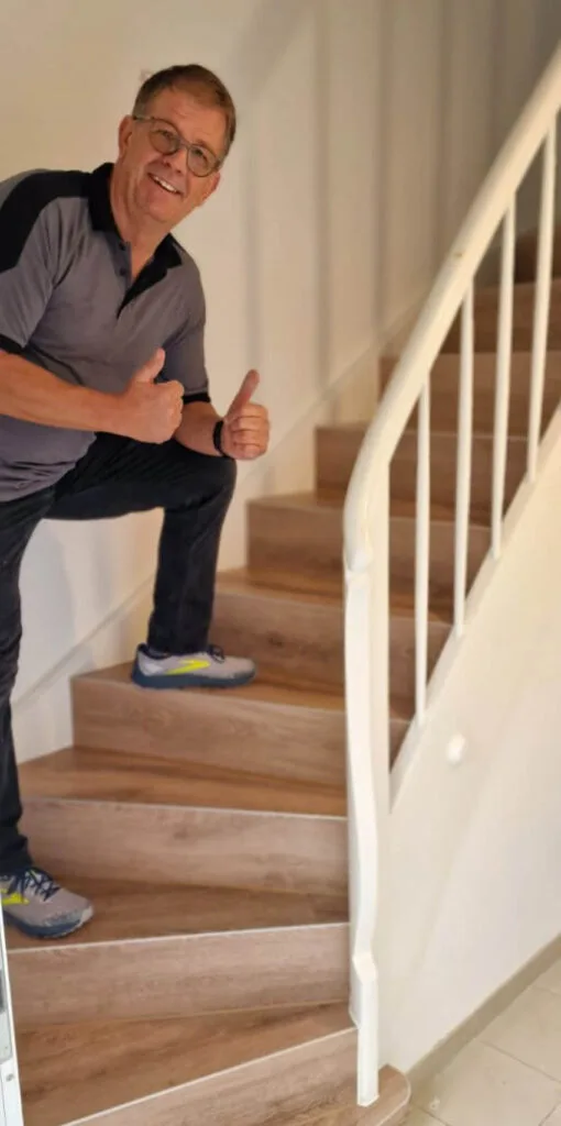 Mann gibt Daumen hoch auf einer Treppe.