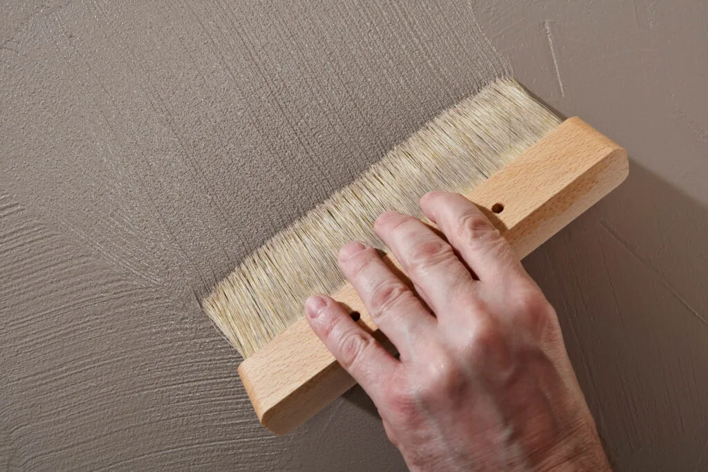 Hand streicht Wand mit Pinsel