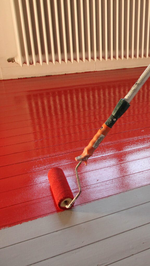 Roter Farbroller auf einem Fußboden